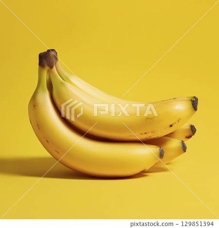 Bunch of ripe bananas, one casually laying atop others, basking in vibrant yellow backdrop, evokes feelings of warmth and simple joy Bunch of ripe bananas, one casually laying atop others, basking in vibrant yellow backdrop, evokes feelings of warmth and simple joy 129851394
