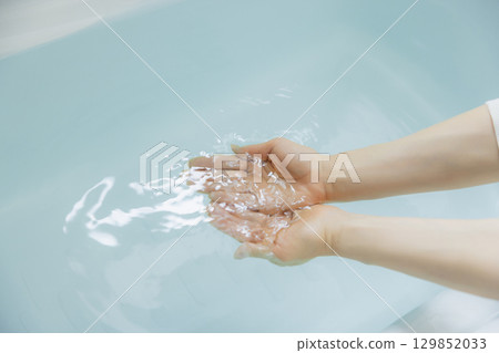 Woman's hand scooping hot water 129852033