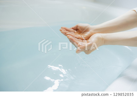 Woman's hand scooping hot water Woman's hand scooping hot water 129852035