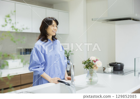 Woman holding a vase in the kitchen 129852085