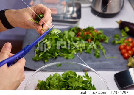 Hands Skillfully Cutting Fresh Cilantro for Delicious and Flavorful Cooking Dishes 129852971