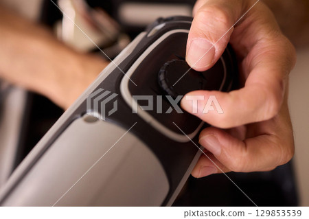 Hand Operating a Sleek and Modern Grooming Device Designed for Personal Care and Hair Styling Hand Operating a Sleek and Modern Grooming Device Designed for Personal Care and Hair Styling 129853539