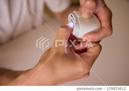 Close-up of an electric nail clipper in hand, modern personal care technology, highlighting compact design and functionality, modern gadget for personal grooming Close-up of an electric nail clipper in hand, modern personal care technology, highlighting compact design and functionality, modern gadget for personal grooming 129853612
