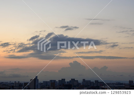 At dawn in Toshi, the sun rises through the gaps between the buildings, casting the area in an orange hue and making the buildings appear as silhouettes. 129853923