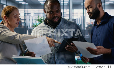 Diverse team of associates engaging in decision making and corporate leadership activities with a focus on foresight and negotiation. Multicultural business development. Camera B. 129854011