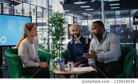 Business meeting in corporate office involving executive decision making, strategic thinking and planning. Diverse professionals ensure organizational growth and performance metrics. Camera A. 129854036