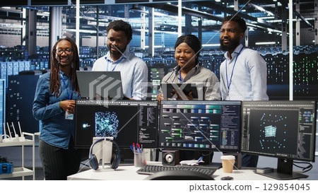 Smiling server hub engineers collaborating, using AI algorithms and node tree systems to categorize unstructured data. Colleagues use visual programming and natural language processing tools, camera A 129854045