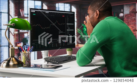 Upset broker distraught after losing money in cryptocurrency, falling for investment scam due to rug pull. Unhappy worried guy in bankruptcy crisis, financial loss after risky trade. Camera B. Upset broker distraught after losing money in cryptocurrency, falling for investment scam due to rug pull. Unhappy worried guy in bankruptcy crisis, financial loss after risky trade. Camera B. 129854048