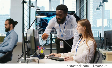 Startup office manager congratulates young girl after developing artificial intelligence models for business analytics. Team leader doing fist bump with female engineers pleased by work done, camera A 129854060