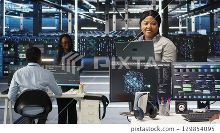 Cheerful data center employee using node tree software to analyze datasets. Upbeat server facility engineer using visual programming to improve infrastructure performance, camera A Cheerful data center employee using node tree software to analyze datasets. Upbeat server facility engineer using visual programming to improve infrastructure performance, camera A 129854095