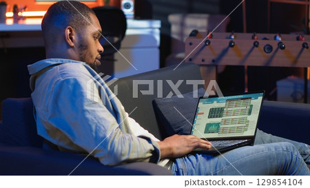 Economic researcher checking monthly balance online on laptop, working on reducing costs to increase profit. Financial advisor examining global investment funds, expansion strategy. Camera B. 129854104