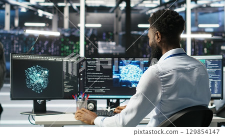 Manager supervising data center engineer using AI neural network models to configure hardware. Team leader overseeing employee using machine learning programming language to optimize systems, camera B 129854147