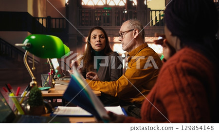 African american woman asking people to keep quiet in the library, struggling to read a book due to noise and disrespect. Making a polite request for the library etiquette. 129854148