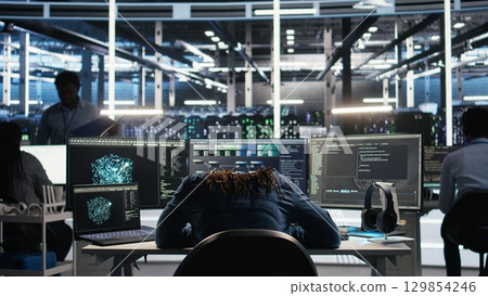 Irked data center IT expert smashing desk, upset by malfunctioning gear while using node tree software. Mad server hub engineer disgruntled by errors, using glitching AI visualization tech, camera A Irked data center IT expert smashing desk, upset by malfunctioning gear while using node tree software. Mad server hub engineer disgruntled by errors, using glitching AI visualization tech, camera A 129854246