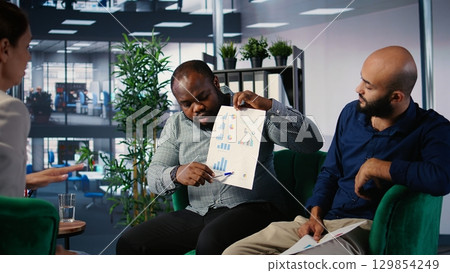Strategic planning session among empowered business people focused on goal oriented metrics and partnership opportunities. Working on a success story in multicultural environment. Camera A. 129854249