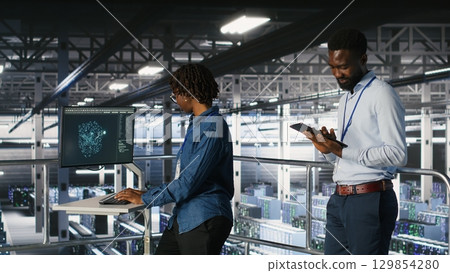 Engineers working together on data center industrial platform, completing software updates. Server hub colleagues doing brainstorming, finetuning server rig configurations Engineers working together on data center industrial platform, completing software updates. Server hub colleagues doing brainstorming, finetuning server rig configurations 129854280