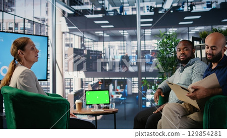 Business associates doing kpi analysis next to isolated device screen, strategic planning session between confident leaders. Powerful people focusing on opportunity for a success story. Camera A. Business associates doing kpi analysis next to isolated device screen, strategic planning session between confident leaders. Powerful people focusing on opportunity for a success story. Camera A. 129854281
