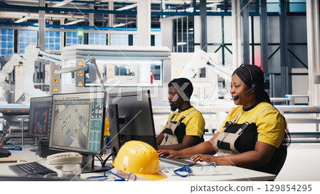 Customer support black engineer at help desk in photovoltaic facility answering calls on headset, offering assistance and support in fixing technical issues. Female operator on help line. Camera B. 129854295