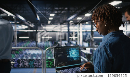 System administrators in data center monitoring AI LLM visualization. African american server farm coworkers overseeing rigs powering machine learning processes, System administrators in data center monitoring AI LLM visualization. African american server farm coworkers overseeing rigs powering machine learning processes, 129854325