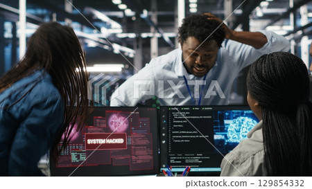 Technicians in AI server hub collaborate to protect against data theft during active threat. Data center team working together to safeguard equipment and systems during security breach, camera B 129854332