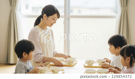 Nursery teachers and children prepare lunch 129854372