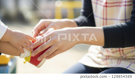 Nursery teachers help children put on their shoes 129854389