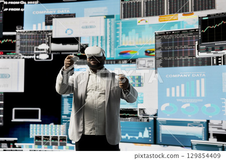 Business leader working with virtual reality headset to obtain new funds, reviewing monthly performance reports on dashboards for development plan. 3d simulation to analyze financial situation. 129854409