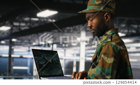 Drone operators in military data center supervising autonomous flight systems through laptop interface. Teamworking army IT experts doing live drone tracking using notebook Drone operators in military data center supervising autonomous flight systems through laptop interface. Teamworking army IT experts doing live drone tracking using notebook 129854414