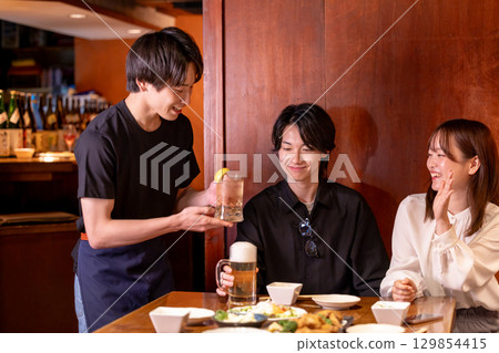 Izakaya: Male staff taking orders on smartphone 129854415