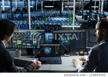 Data center technicians monitoring AI applications, adjusting machine learning parameters. Teamworking server hub workers collaborating, enhancing artificial intelligence software performance 129854430