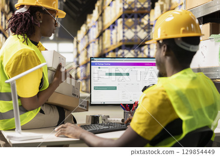 Fulfillment center staff updating the package tracking software with route details and other information for clients, overseeing e-commerce orders for express delivery. Dispatch coordination. 129854449