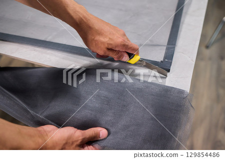 Hand Assembling a Frame on a Beautiful and Modern Table in a Creative Workspace 129854486