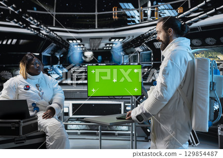 Researchers travelling in space with starship conducting scientific experiments in orbit using green screen monitor. Scientists using mockup display to document experimental observations Researchers travelling in space with starship conducting scientific experiments in orbit using green screen monitor. Scientists using mockup display to document experimental observations 129854487