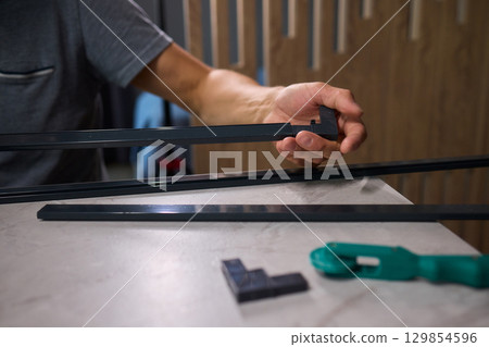 Hand Assembling a Frame on a Beautiful and Modern Table in a Creative Workspace Hand Assembling a Frame on a Beautiful and Modern Table in a Creative Workspace 129854596