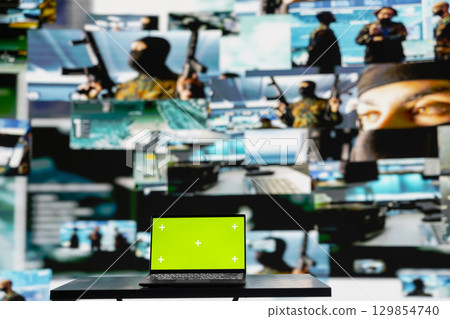 Green screen on laptop next to military satellite imagery of enemy forces, high tech armed forces command center used to gather data helpful for war planning. Secure global operations. 129854740