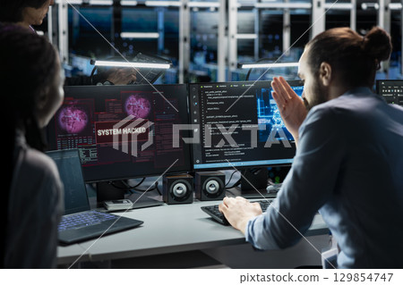 Technicians in AI server farm doing brainstorming to fix hacking incident involving theft of sensitive data. Data center coworkers working together to stop computer virus triggered by security systems 129854747