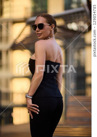 An Elegant Woman in a Stylish Outfit Stands Beautifully at Sunset, Radiating Confidence An Elegant Woman in a Stylish Outfit Stands Beautifully at Sunset, Radiating Confidence 129854785