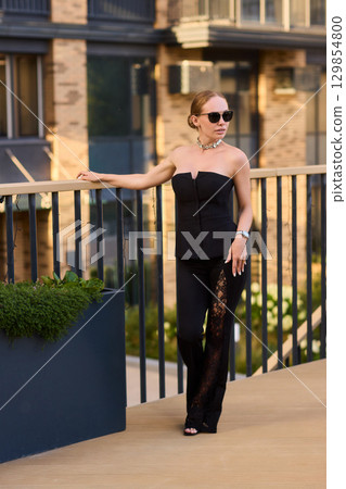 An Elegant Woman in a Stylish Outfit Stands Beautifully at Sunset, Radiating Confidence An Elegant Woman in a Stylish Outfit Stands Beautifully at Sunset, Radiating Confidence 129854800