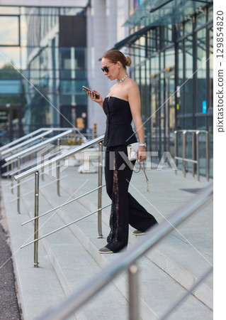 A Stylish and Fashionable Woman Dressed in Elegant Black Attire, Complete with Chic Sunglasses 129854820