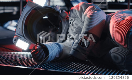 Cosmonaut collapses from sudden illness during major space station failure starting red light alert. Warning lights flashing over unconscious astronaut suffering medical crisis in spacecraft Cosmonaut collapses from sudden illness during major space station failure starting red light alert. Warning lights flashing over unconscious astronaut suffering medical crisis in spacecraft 129854836
