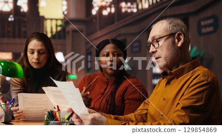 Diverse actors team reading their scripts during theatre drama play rehearsal in library, showing dedication to script practice. Role preparation together for dramatic arts reenactment. 129854869