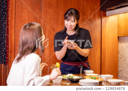 居酒屋:女店員透過智慧型手機接單 居酒屋:女店員透過智慧型手機接單 129854878