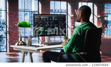 African american engineer at home working on visual coding on terminal window, typing programming language and reviewing the notes tree. IT expert using debugging algorithms to fix errors. Camera A. 129854884