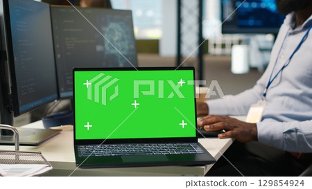 Technician next to office coworkers developing software applications using green screen laptop, integrating AI automation. IT expert debugging applications with mockup notebook, camera A 129854924