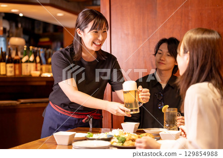 Izakaya: Female staff serving drinks to customers Izakaya: Female staff serving drinks to customers 129854988