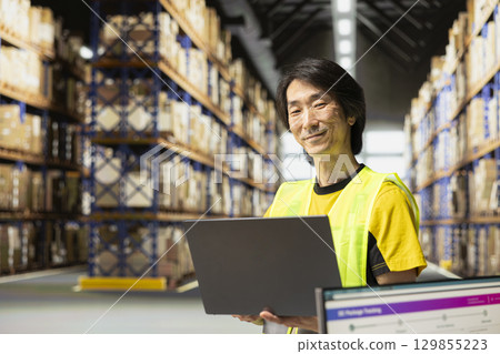 Local shipping operations handled in-house by asian man in fulfillment center, employees managing orders and ensuring the small business meets high standards for e-commerce delivery service. 129855223