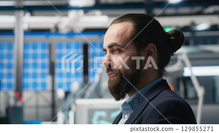 Professional consultant reviewing solar power quality in a factory, reviewing data reports and insight for seamless production line and sustainable solar energy. Photovoltaics industry. Camera B. 129855271