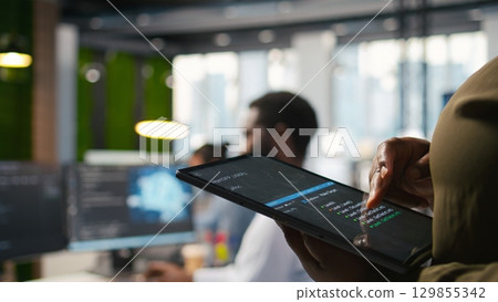 Close up of programmer utilizing AI on tablet to optimize performance and forecast issues. System administrator in office training machine learning models using device, camera A Close up of programmer utilizing AI on tablet to optimize performance and forecast issues. System administrator in office training machine learning models using device, camera A 129855342