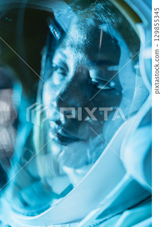 Close up of ill astronaut in cold spaceship chamber after temperature control failure causes severe heat loss. Frozen woman dying in orbital station after conditions drop below survival limit Close up of ill astronaut in cold spaceship chamber after temperature control failure causes severe heat loss. Frozen woman dying in orbital station after conditions drop below survival limit 129855345