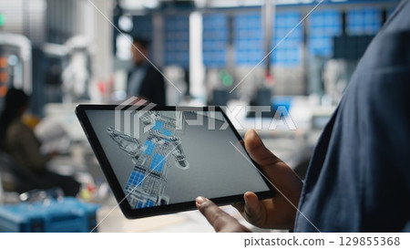 Solar power technician reviewing data on tablet in photovoltaics factory, inspecting manufacturing plant performance and production line for solar innovation. Alternative energy. Camera A. 129855368